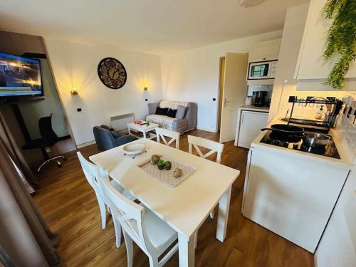 une cuisine et un salon avec une table et des chaises blanches dans l'établissement 