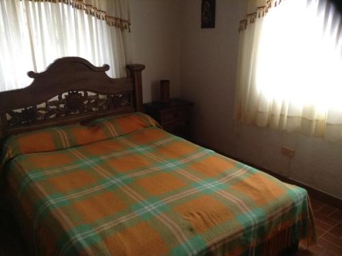 a bedroom with a bed with a green and orange blanket at Villa Liliana Lodge Mesa de los Santos in Los Santos