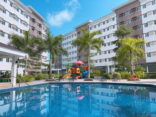 a pool with a playground in front of a building at Cozy Belle Suite Relaxing Place at SMDC Hope Residences in Trece Martires