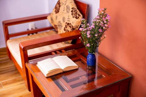 a table with a book and a vase of flowers on it at Leila House - DaNang Central - 3BRs - Free Airport Shuttle in Da Nang