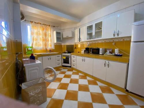 - une cuisine avec des placards blancs et un sol en damier dans l'établissement Spacious Cozy Appartment Akid Lotfi ORAN, à Oran