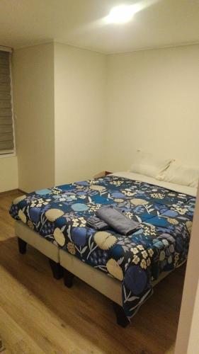 a bedroom with a bed with a blue and white blanket at Apartamento La Florida Mirador Oriente in Santiago