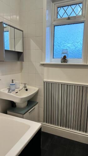 a white bathroom with a sink and a window at Ur Place 204 in Manchester
