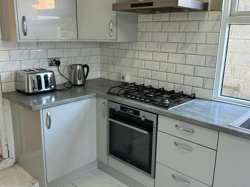 a kitchen with white cabinets and a stove top oven at ELSARO guest house in Slough