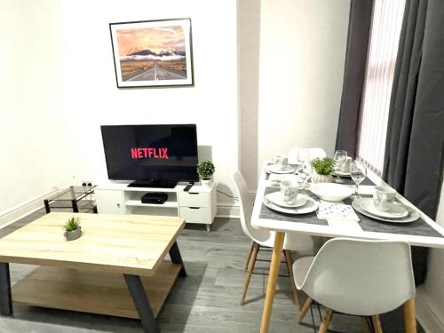 a dining room with a table and a tv at Cosy Spacious Family & Contractor Friendly 3 Bedroom House Near Liverpool Centre Sleeps 6 in Liverpool
