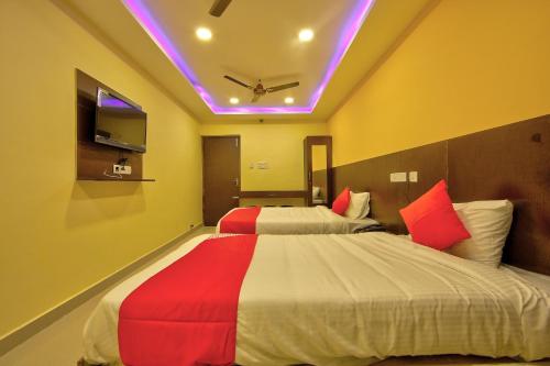 um quarto com 2 camas com lençóis vermelhos e brancos em Collection O Joliday Inn em Mahabalipuram