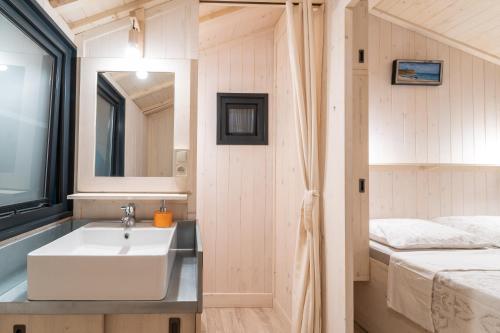 bagno con lavandino e letto di Camping Arutoli a Porto Vecchio