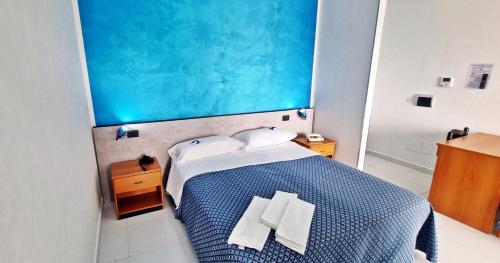 una camera con un letto blu e bianco con due asciugamani bianchi di Hotel Blu Eden a Praia a Mare