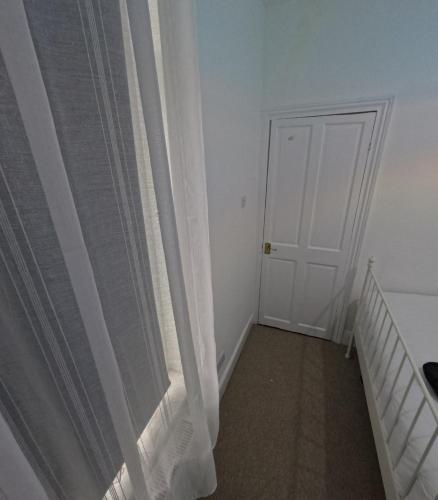 a bedroom with a white door and a curtain at King Size Bed Room with Private Gym Access in Portsmouth