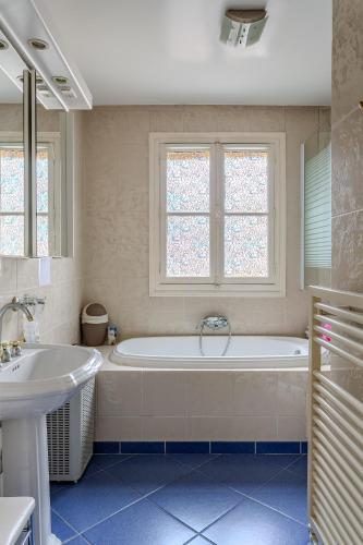 une salle de bain blanche avec une baignoire et un lavabo dans l'établissement SACRE COEUR Grand Duplex 130 m2 - 4 chambres + double living, à Paris