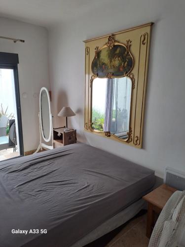 une chambre avec un lit et un miroir au mur dans l'établissement Belle maison de village entièrement climatisée, à Vias