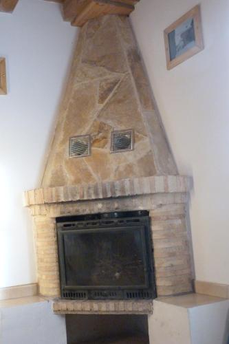 a fireplace with a stone face with a tv at El Farolillo de Piedra in Montejo de Tiermes