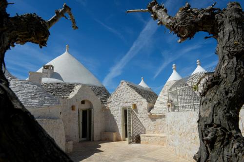 a building with white domes and a tree at Trulli Lisanna - Exclusive Trulli With Private Pool in Antonelli