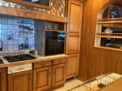 une cuisine avec des armoires en bois et un micro-ondes noir dans l'établissement La croisière, à Étretat