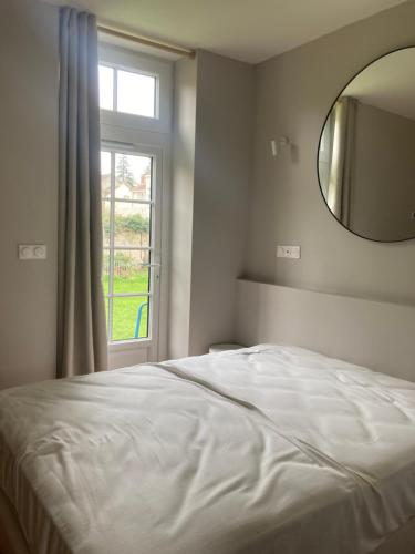 1 dormitorio con cama, espejo y ventana en La maisonette des bords de Seine, en Samois-sur-Seine