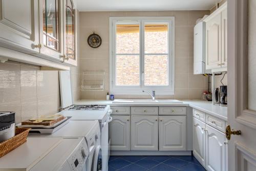 une cuisine avec des armoires blanches, un évier et une fenêtre dans l'établissement SACRE COEUR Grand Duplex 130 m2 - 4 chambres + double living, à Paris
