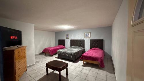 dwa łóżka w pokoju z różową pościelą i telewizorem w obiekcie Hotel y Cabañas Cascada de Basaseachi 