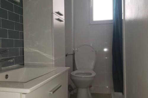 une salle de bain blanche avec toilettes et fenêtre dans l'établissement Bel Appartement Colombes Centre, à Colombes