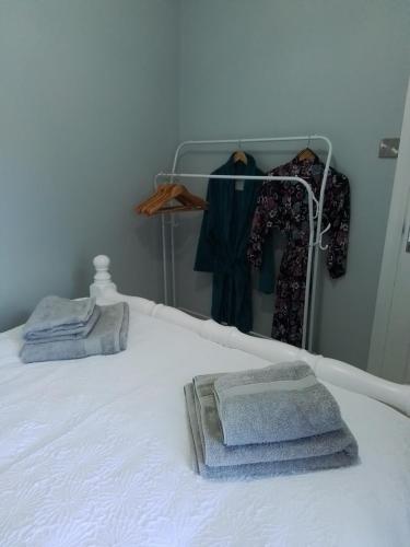 a bed with towels and clothes on a rack at John & Mary's in Dromore