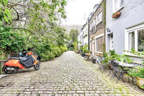 un scooter orange garé sur une rue pavée dans l'établissement Magnificent 2 Bed Hyde Park Mews House, à Londres