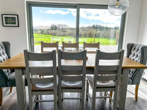 uma mesa de jantar com cadeiras e uma grande janela em Sneem Farmhouse em Sneem