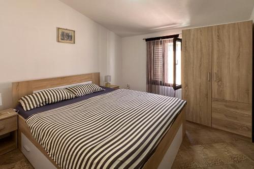 Schlafzimmer mit einem Bett mit einer schwarz-weißen gestreiften Bettdecke in der Unterkunft Pahert Beach Apartment in Vir