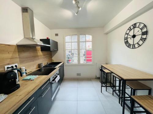une cuisine avec une grande horloge murale dans l'établissement Cosy Appartement Montferrand tout équipé 6prs 27 Languedoc, à Clermont-Ferrand