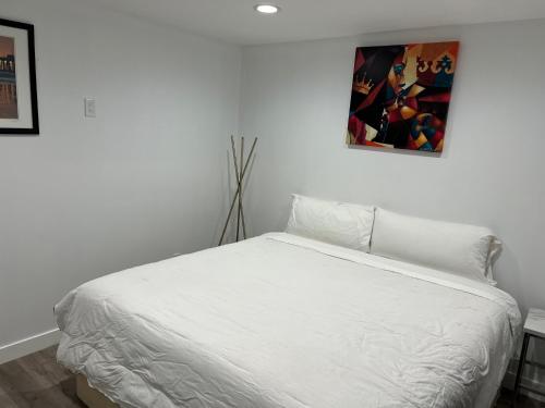 um quarto com uma cama branca e uma pintura na parede em Private 1bedroom & 1bathroom home perfect for 2+ near Universal studio em Van Nuys