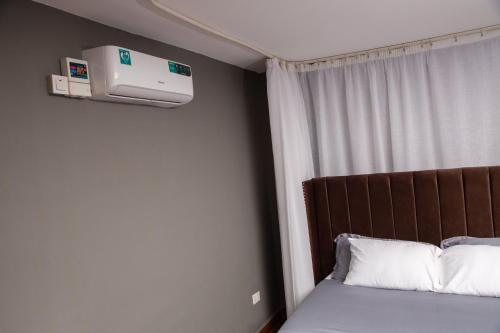 a bedroom with a bed and a air conditioner on the wall at Malixa Lofts in Wakiso