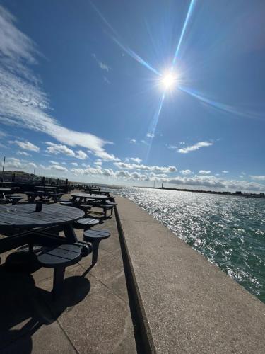 una fila di tavoli da picnic accanto all'acqua di Meadow bay Hayling Island-Iona a South Hayling