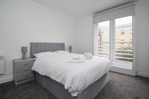 a white bedroom with a large bed and a window at Merchant City Apartment in Glasgow