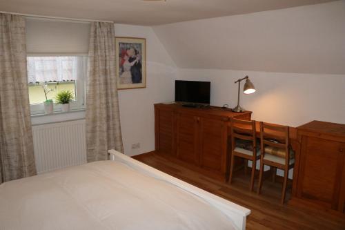 a bedroom with a bed and a desk and a television at Ferienhaus Apfelblüte in Schotten