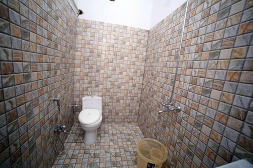 a bathroom with a toilet and a tiled wall at Seasons Inn in Karachi