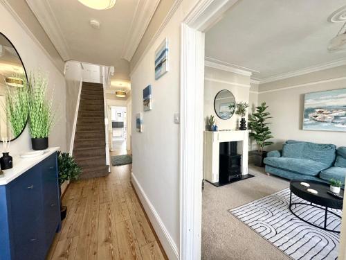 a living room with a blue couch and a staircase at The Capstone Retreat - Beautiful Detached Family Home By Coastline Retreats, Arcade Machine, Parking, BBQ in Bournemouth