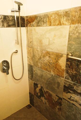 a bathroom with a shower with a tiled wall at VILLA SIMONE ARENAL French Ecolodge in Tilarán