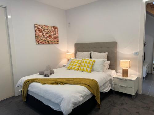 Un dormitorio con una cama grande con almohadas amarillas y blancas en Geelong Luxury Beach K Villa, en North Shore