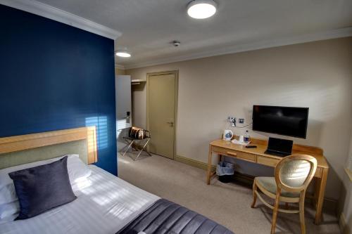 a bedroom with a bed and a desk with a television at The Rochford Hotel in Southend-on-Sea