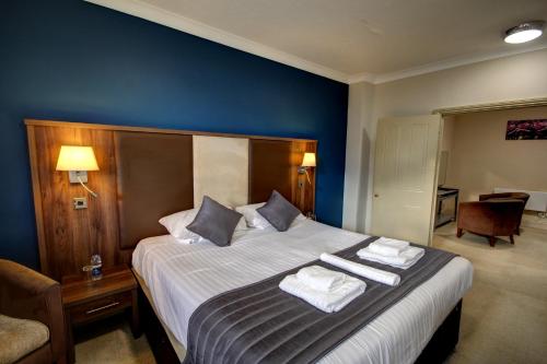 a bedroom with a large bed with towels on it at The Rochford Hotel in Southend-on-Sea