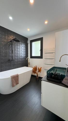 La salle de bains est pourvue d'une grande baignoire blanche et d'un lavabo. dans l'établissement Maison d'Exception pour un Séjour Inoubliable, à Villetelle