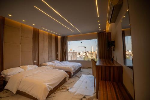 two beds in a hotel room with a window at New Cairo Airport Studio in Cairo