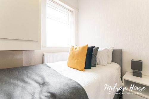 a bedroom with a bed with a yellow pillow on it at Melrose Contractor Accommodation in Manchester