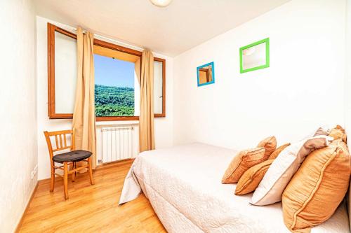 une chambre avec un lit, une fenêtre et une chaise dans l'établissement Locations-06 La maison de Noélie 1er étage, gite pour 6 au calme sur la Côte d'Azur, à Le Bar-sur-Loup