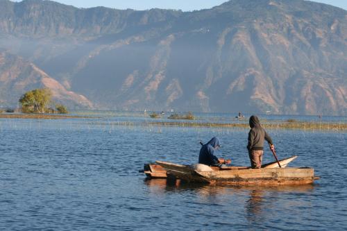 two people are sitting on a boat in the water at Anzan Atitlan in San Marcos La Laguna