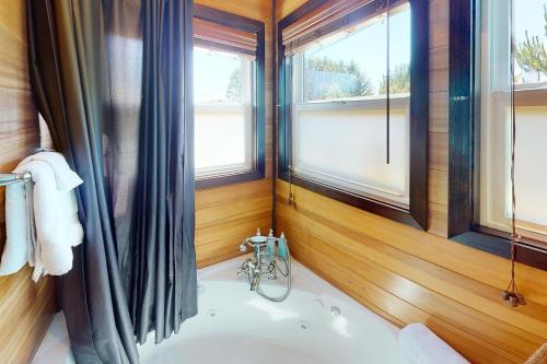 a bathroom with a tub in a room with windows at Evergreen in Waldport