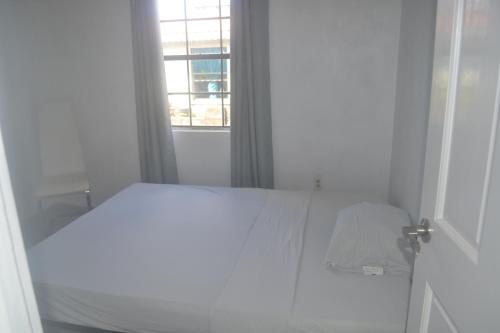 a white bed in a white room with a window at Cozy Tropical Escape no 112 in Saint Peter