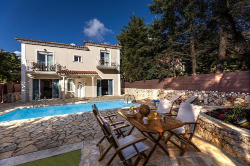 een villa met een zwembad en een tafel en stoelen bij Villa Kataleya in Svoronata