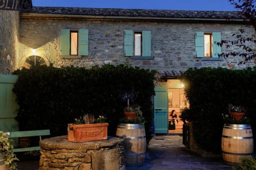 a stone house with green doors and barrels in front at Locanda Del Molino in Cortona
