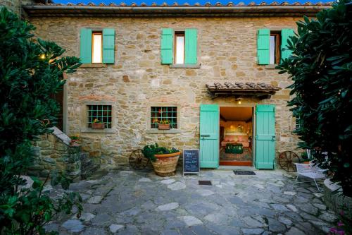 a stone house with green shutters on it at Locanda Del Molino in Cortona