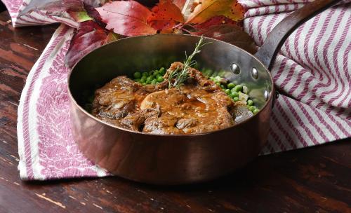 a metal pot with meat and peas on a table at Locanda Del Molino in Cortona