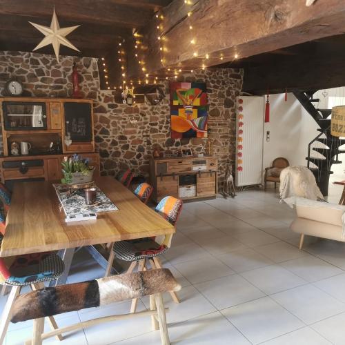 - un salon avec une table en bois et un mur en pierre dans l'établissement LA FEE VIVIANE, à Villerest